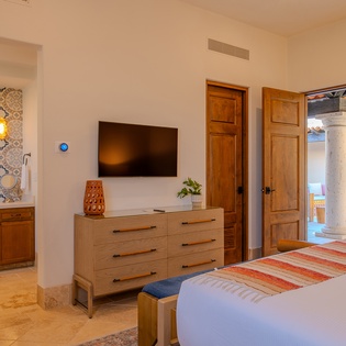 Unwind in your elegant bedroom suite with warm wood finishes, flat-screen TV, and charming en-suite bathroom featuring beautiful patterned tiles.