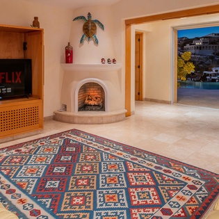 Unwind in your cozy living room with Netflix, a crackling fireplace, and stunning oceanside views through open doors.
