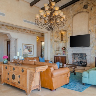 Relax in your elegant living space with soaring ceilings, stone fireplace, and rich furnishings creating a perfect blend of luxury and comfort.