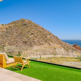 Stunning hilltop terrace overlooks coastal landscape and blue ocean beyond the natural vegetation.