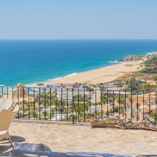 Sweeping ocean views await from your private terrace, where comfortable seating and vibrant flowers frame the stunning coastline below.