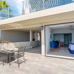 Slide open the glass doors to your covered patio where outdoor dining meets indoor comfort under tropical palms.