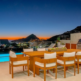 Stunning terrace dining with panoramic mountain and sea views at twilight, complete with pool and outdoor kitchen for memorable evenings.