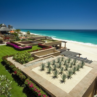 Stunning beachfront property features pristine white sand and crystal-clear turquoise waters just steps from meticulously landscaped gardens.
