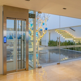Step into a stunning modern lobby with floor-to-ceiling glass, illuminated staircase, and an elegant water feature creating a luxurious arrival experience.