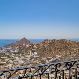Elevated terrace overlooking coastal mountains and sea with decorative wrought iron railings capturing the scenic landscape.