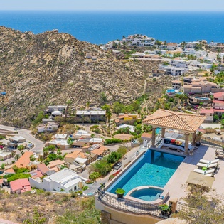 Stunning aerial view of coastal community with desert hills meeting azure ocean waters.