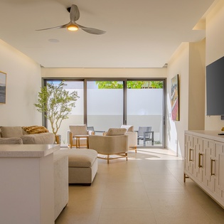 Relax in your bright, modern living space with plush seating and peaceful patio views through floor-to-ceiling windows.