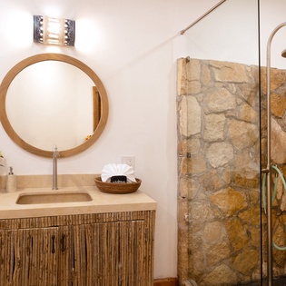 Unwind in your spa-like bathroom featuring natural stone shower walls, warm wood accents, and elegant rainfall fixtures.
