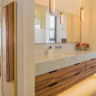 Unwind in your spa-inspired ensuite with floating marble vanity, warm wood accents, and golden pendant lighting creating a luxurious sanctuary.