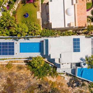 Aerial view of modern vacation property featuring swimming pools, tropical gardens, and contemporary architecture in a serene residential setting.