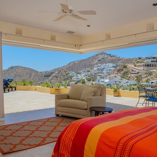Wake up to sweeping hillside views from your spacious bedroom, where vibrant linens and a private terrace create the perfect retreat.