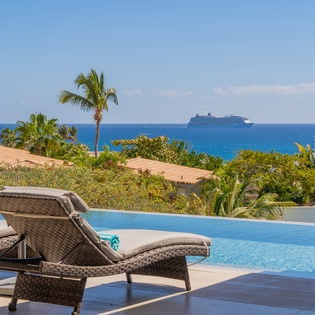 Unwind on comfortable loungers beside your private infinity pool, with tropical palms and ocean views creating the perfect paradise backdrop.