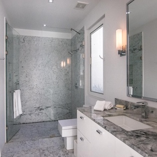 Step into your luxurious marble bathroom featuring a spacious glass-enclosed shower and elegant vanity for ultimate relaxation.