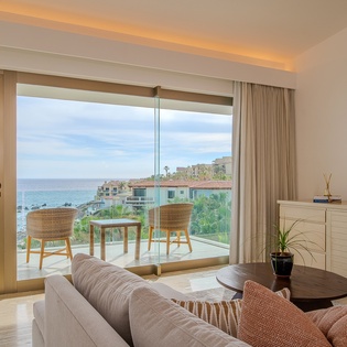 Unwind in your bright living space where ocean views stretch endlessly beyond floor-to-ceiling windows and your private terrace awaits.