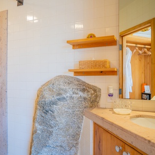 Your spa-like bathroom features natural stone, warm wood, and a rainfall shower for ultimate relaxation after your adventures.