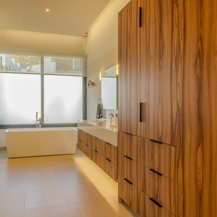 Step into your spa-like sanctuary with warm wood cabinetry, a soaking tub, and sleek modern design creating the perfect retreat.