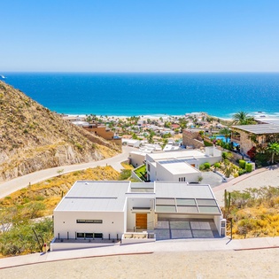 Modern hillside property overlooking pristine beach and turquoise waters in an exclusive coastal community.