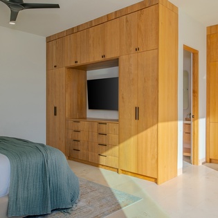Relax in your beautifully designed bedroom featuring custom wood cabinetry, built-in entertainment center, and modern amenities for the perfect stay.