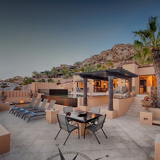 Expansive terrace overlooks dramatic hillside views, featuring poolside loungers, covered dining, and an evening fire feature—your private retreat in the hills.