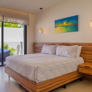 Rest peacefully in your serene bedroom with warm wood accents, modern pendant lighting, and garden views through floor-to-ceiling windows.