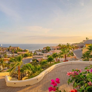 Hillside coastal community with ocean views and tropical vegetation at golden hour.
