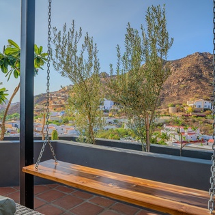 The hillside and neighborhood stretch beyond this charming outdoor spot, offering a scenic backdrop for the property's location and surrounding area.