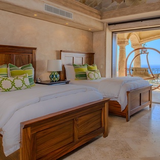 Wake up to stunning ocean views from your elegant twin bedroom, where rich wood furnishings and vibrant green accents create coastal luxury.