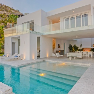 Modern villa with infinity pool seamlessly blending luxury and coastal landscape in an exclusive hillside setting.