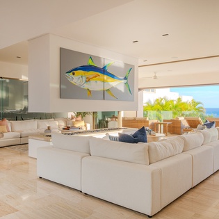 Your spacious living room flows seamlessly to ocean views, where plush sofas invite relaxation by the modern fireplace.
