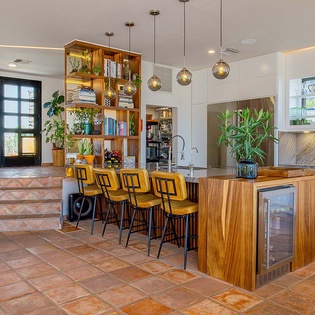 Gather around this stunning kitchen island with stylish bar seating, pendant lighting, and a wine cooler at your fingertips—perfect for morning coffee or evening cocktails.