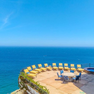Imagine lounging on your private sun terrace with endless blue ocean views. This Mediterranean-style patio offers comfortable seating, a dining table for al fresco meals, and the soothing sound of waves below.
