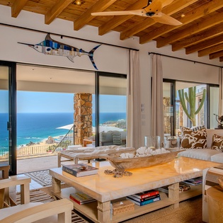 Sink into plush seating while panoramic ocean views stretch endlessly before you through floor-to-ceiling windows in this stunning coastal retreat.