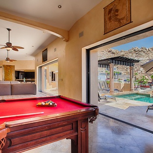 Step into your game room where billiards meets desert beauty—large glass doors open to your private pool, framed by mountain views that make every moment unforgettable.