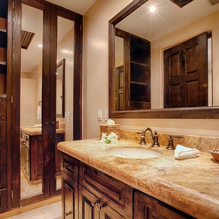 Unwind in your private bathroom featuring a spacious marble vanity, rich wood cabinetry, and warm lighting that creates a welcoming, spa-like retreat after a day of adventure.