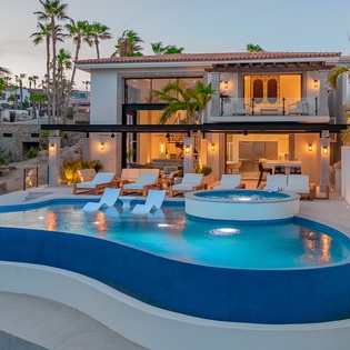 Modern luxury villa with pristine swimming pool and hot tub, surrounded by tropical palms in an upscale neighborhood setting.