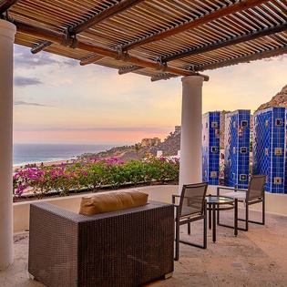 Relax under a shaded pergola with captivating ocean and hillside views, where vibrant bougainvillea and handcrafted tile details invite you to unwind in your coastal sanctuary.
