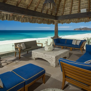 Your private beachfront palapa offers front-row seats to paradise, where you can relax on plush blue cushions while turquoise waters stretch endlessly before you.