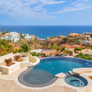Elevated property showcasing a private pool and hot tub overlooking a coastal neighborhood with sweeping ocean views beyond.