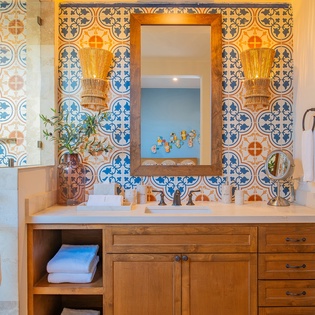 Immerse yourself in Mediterranean charm with stunning hand-painted tiles, warm wood vanity, and spa-inspired amenities in your private bathroom retreat.