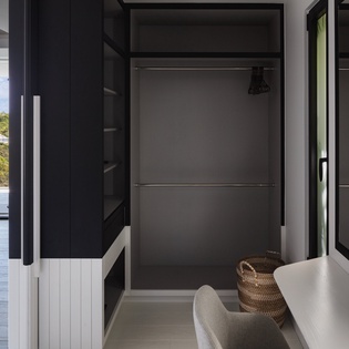 Your spacious walk-in closet features sleek storage and hangers, with natural light streaming in from your ocean-view terrace.