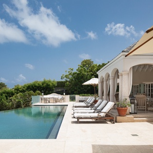 Stretch out on plush loungers beside your private infinity pool, where elegant arches frame tropical vistas and the sparkling water blends seamlessly with the horizon.