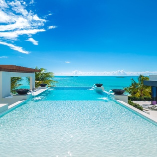 Modern infinity pool showcasing brilliant turquoise waters that blend seamlessly into the horizon, framed by contemporary architecture and lush tropical greenery.