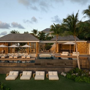 Stunning tropical villa featuring expansive pool deck, luxury lounge areas, and palm-fringed architecture in an exclusive resort setting.