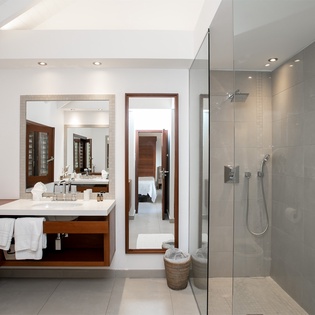 Step into your private spa-like retreat, where sleek gray tiles and warm wood tones create a peaceful sanctuary for your daily refresh.