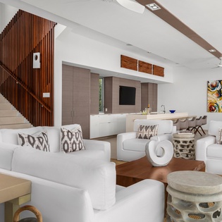 Sink into plush white sofas in your open-plan living space, where modern art and warm wood tones create the perfect retreat.