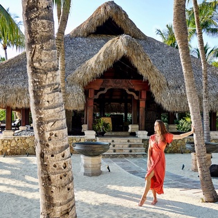 Traditional thatched-roof architecture surrounded by swaying palms creates an authentic tropical island atmosphere.