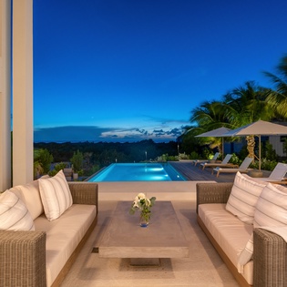 Luxurious beachfront villa with infinity pool, tropical palms, and stunning twilight views for your perfect island getaway.