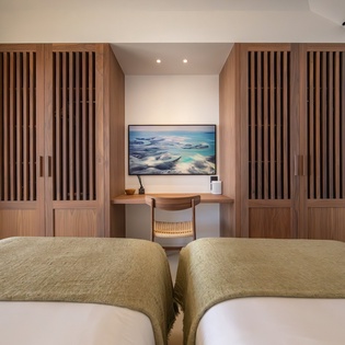 Your serene twin bedroom features rich wood paneling and a cozy workspace, perfect for restful nights and productive moments.