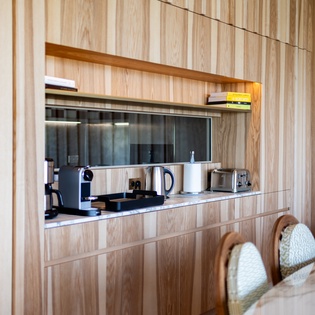 Your sleek kitchenette nook features modern appliances perfectly tucked into warm wood cabinetry, creating an efficient cooking space.